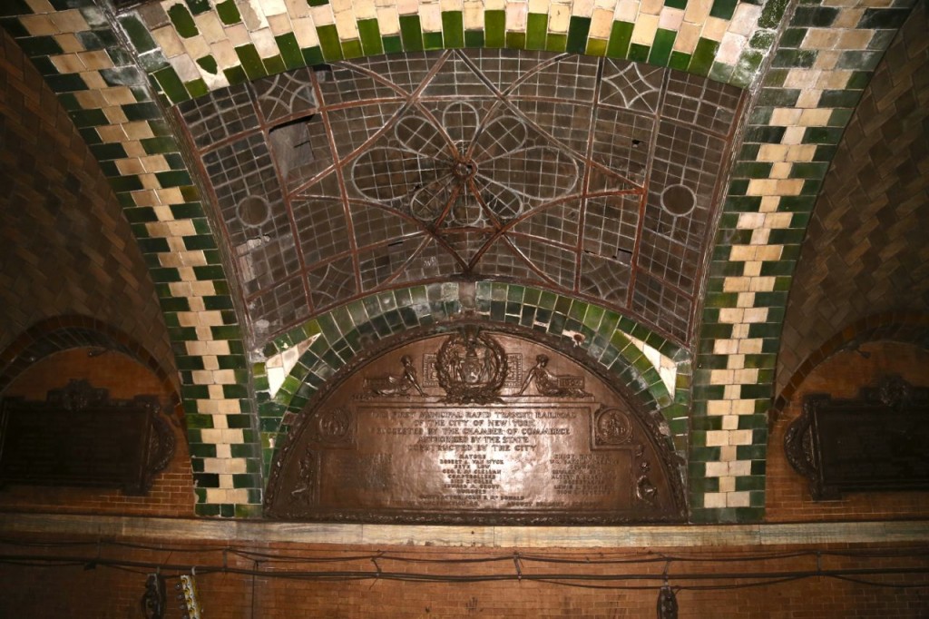 The middle arch on the platform where the passageway from the mezzanine ends. The arch has three skylights. Opposite the passageway are three plaques commemorating those who helped in the station's creation.