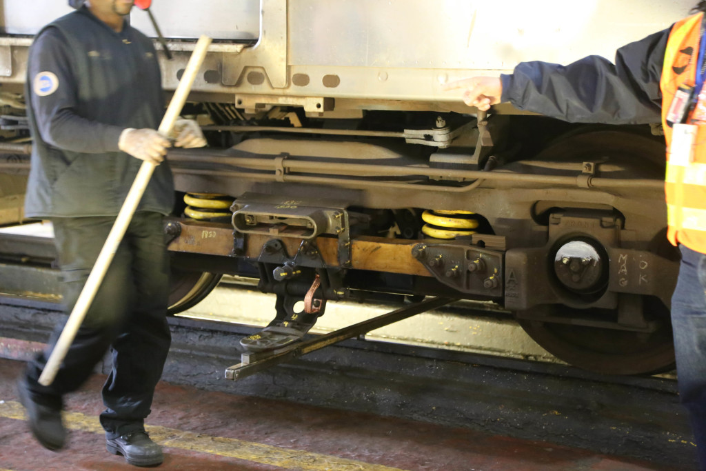 A stick is used to make sure the contact shoe is at the right height. A maintenance worker is carrying another stick used to measure the height of the car above the rail.