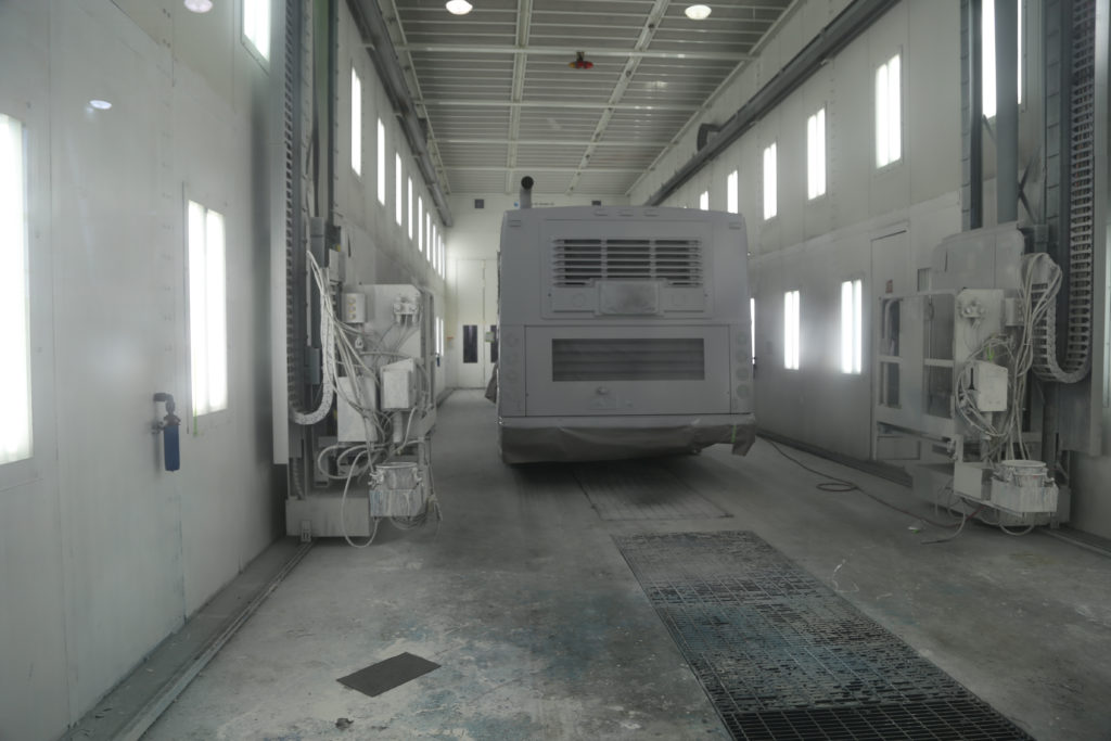 Bus in paint booth. Machine on wall is a platform with spray gun for a painter to paint from.