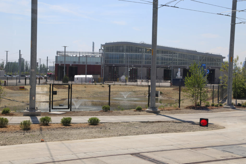 Stormwater retention pond in middle of storage yard with facility in background