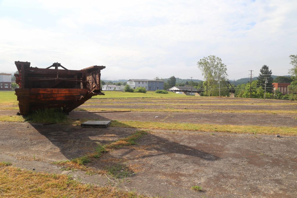 Alternating concrete and grass of roundhouse with rail bridge truss in background