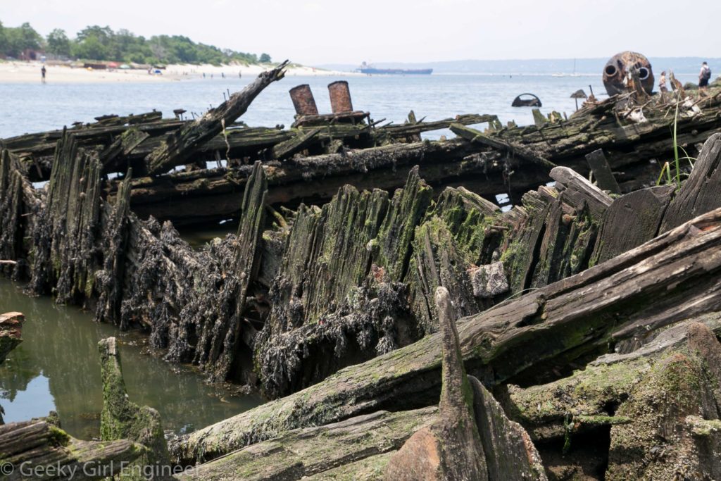 Wooden shipwreck with large modern tanker ship in background